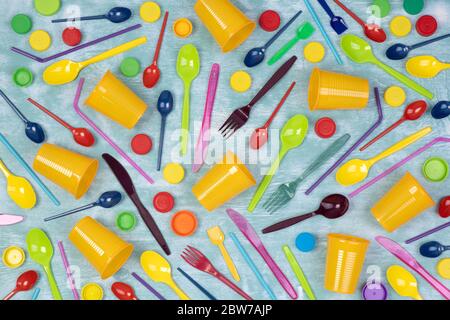 Disposable single use plastic objects such as cups, forks and spoons and drinking straws on blue background, top view Stock Photo