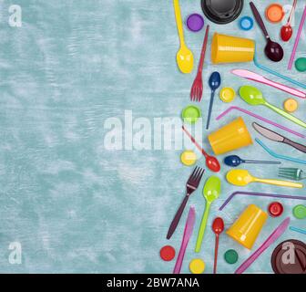 Disposable single use plastic objects such as cups, forks and spoons and drinking straws on blue background, top view Stock Photo