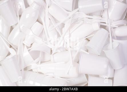Disposable white single use plastic objects such as bottles, cups, forks and spoons that cause pollution of the environment Stock Photo