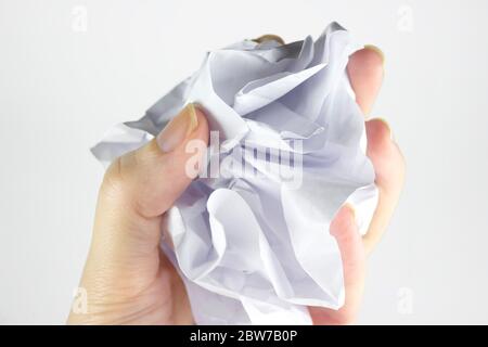 A woman's hand holds a crumpled paper ball with a copy of space on a gray background. Crumpled paper in hand, hand and crumpled paper, on a white back Stock Photo