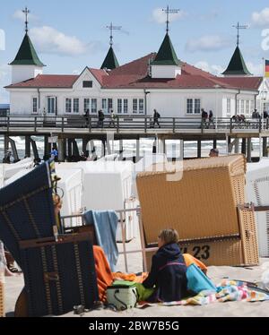Ahlbeck, Germany. 30th May, 2020. A woman is sitting on the Baltic beach behind beach chairs in front of the pier in Albeck on the island of Usedom. Credit: Stefan Sauer/dpa-Zentralbild/dpa/Alamy Live News Stock Photo