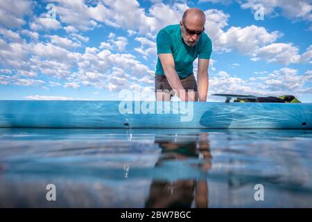 senior male paddler is preparing his stand up paddleboard for morning paddling workout, solo paddling as fitness and training with social distancing, Stock Photo