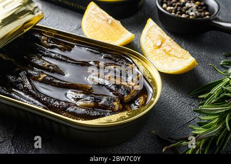 Top viTop view of opened cans with sprats on grey textured stone table,with herbs rosemary Stock Photo