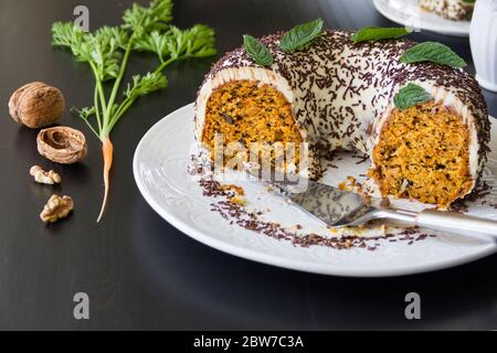 Homemade carrot cake on a large white dish on a dark wooden table. Selective focus, copy space Stock Photo