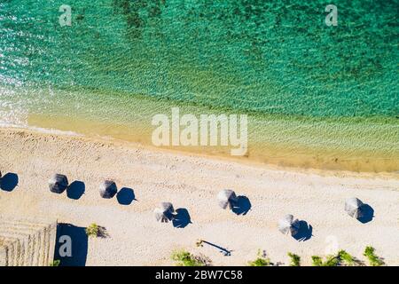 Adriatic sea shore in Croatia on Pag island, beautiful sand beach with parasols, overhead view from drone