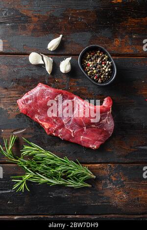 Flank, Bavette steak with seasonings, and fresh herbs raw meat, marbled beef . Dark wood rustic background. Top view. Stock Photo