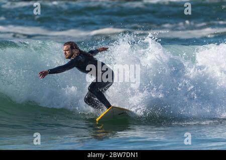 Spectacular action as a male surfer rides a wave at Fistral in Newquay in Cornwall. Stock Photo