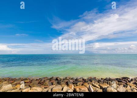 Tropical sea or ocean, view from wavebreaker build from stones and rocks. Horizon over sea with blue sky Stock Photo