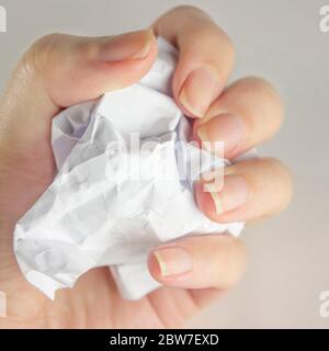 A woman's hand holds a crumpled paper ball with a copy of space on a gray background. Crumpled paper in hand, hand and crumpled paper, on a white back Stock Photo