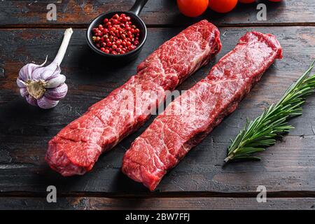 Raw denver steak or organic top blade wuth herbs on old wooden planks surface side view. Stock Photo