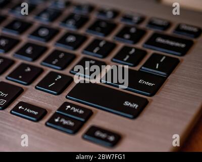 Closeup of laptop keyboard, Black keys on silver laptop. Enter key in focus. Stock Photo