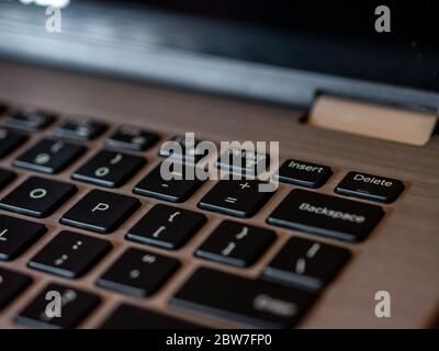Closeup of laptop keyboard, Black keys on silver laptop. Delete key in focus. Stock Photo