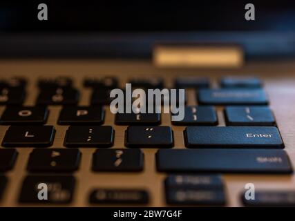 Closeup of laptop keyboard, Black keys on silver laptop. Enter key in focus. Stock Photo