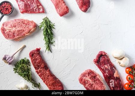 Set of different alternative types of raw beef steaks,on a white stone background top view concept frame in corners space for text in center. Stock Photo