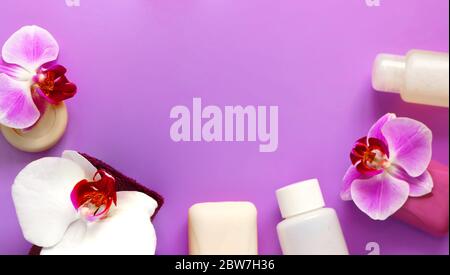 Soap, towel and hygiene product, decorated with white and lilac orchid flowers on a lilac background. Spa concept Stock Photo