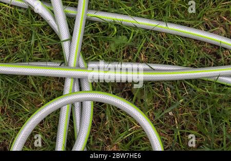 Top view of hosepipe on grass and cobblestone surfaces. Minimalistic conception. Stock Photo