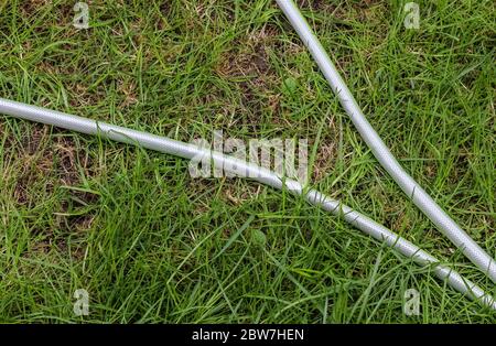 Top view of hosepipe on grass and cobblestone surfaces. Minimalistic conception. Stock Photo