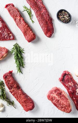 Set of different alternative types of raw beef steaks,on a white stone background top view concept frame in corners space for text vertical in center. Stock Photo