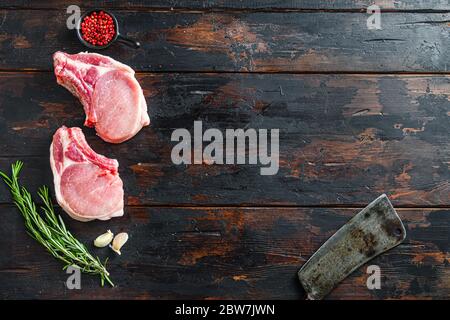 Raw pork meat chopes with herbs and spices with meat american cleaver on dark rustic wooden background side view space for text Stock Photo