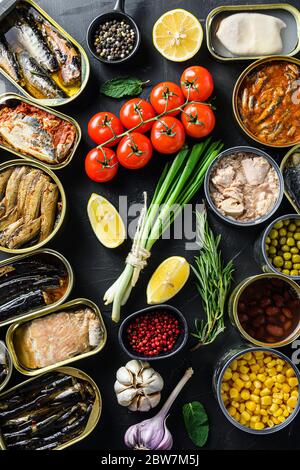 of canned preserves food in cans with fresh organic bio ingredients tomatoe herbs lemon On the black chalkboard Stock Photo