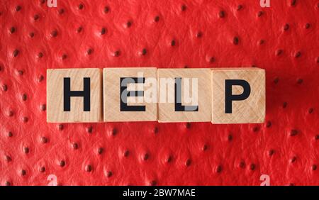Word HELP are written on wooden blocks. Blocks are located on a red background. Support desk , education or business concept Stock Photo