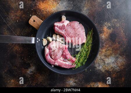 Grilled pork rib chop steak in grill frying pan hot with smoke and hot oil just from fire, top view cooking bone with seasonings rustic metal backgrou Stock Photo