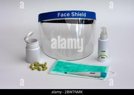 Equipments to combat Coronavirus, face shield, surgical mask, digital thermometer, hand sanitizer, and pills against the virus. Stock Photo