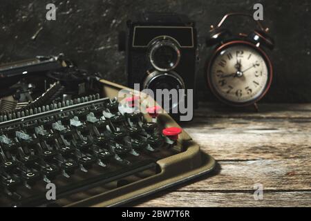 Old retro typewriter, alarm clock and camera on a wooden background Stock Photo