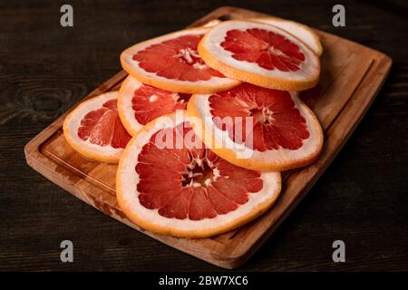 Pile of sliced fresh grapefruit on wooden board ready to be put in domestic fruit dryer to make candied citrus provision for winter Stock Photo