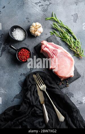 Pork chopes with herbs, spices on black slate over grey background top view Stock Photo