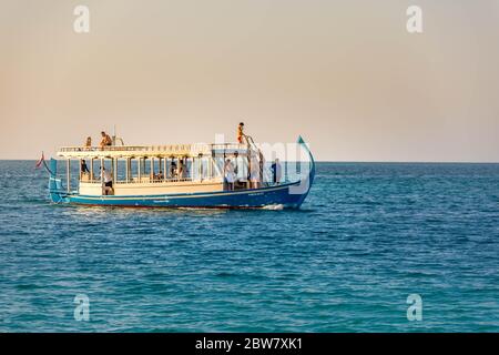 Maldives: Wonderful Maldivian boat Dhoni on tropical blue sea, taking tourist to a sunset cruise. Stock Photo