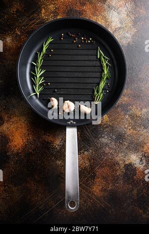 barbecue grill frying pan or skillet on rustic metall surface with herbs for cooking top view concept for text or objects. Stock Photo