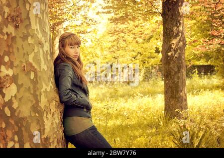 Young woman leaning on a tree in autumn, on the Castrelos Park in Vigo, Galicia Stock Photo