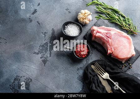 Pork chopes with herbs, spices on black slate over grey background top view. space for text. Stock Photo