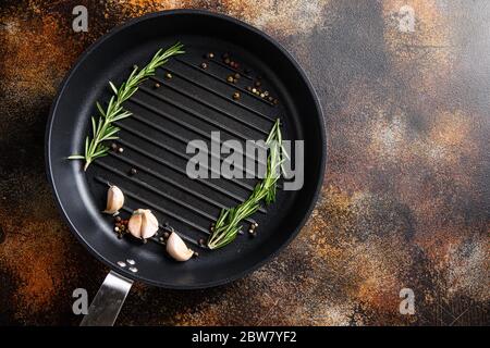 barbecue grill frying pan or skillet on rustic metall surface with herbs for cooking top view concept for text or objects. Stock Photo