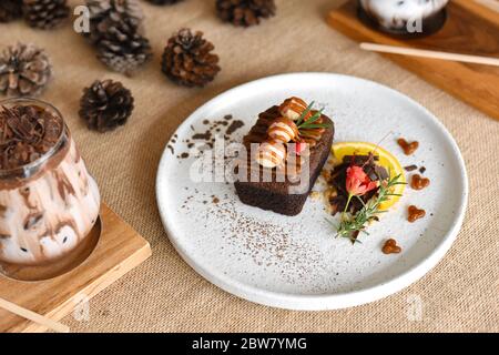 Top view chocolate brownies with on top Macadamia and caramel in the white dish on Sackcloth background. homemade bakery or dessert Decorate with fres Stock Photo
