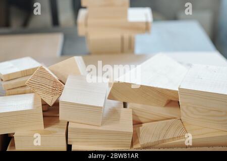Pile of wooden bricks - workpieces for furnishing materials or leftovers - lying on workbench in large workshop of furniture factory Stock Photo