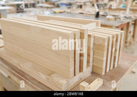 Set of thick large wooden boards or workpieces for production of furniture on workbench of engineer inside workshop of modern factory Stock Photo