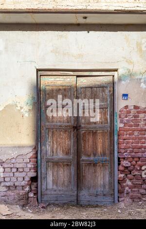 Closed wooden weathered door and shabby old grunge red bricks wall in abandoned district Stock Photo