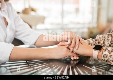 Hands of supportive mother on those of her young worried or upset young daughter as sign of comforting, care and support Stock Photo
