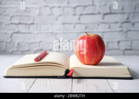 close up of apple on and pencil on open book on table  Stock Photo