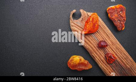 Natural amber. A piece of yellow transparent natural amber on a piece of textured wood, background for design Stock Photo