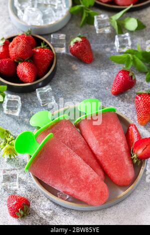 Homemade strawberry frozen fruit juice. Ice cream or popsicles on a light stone or slate table. Stock Photo