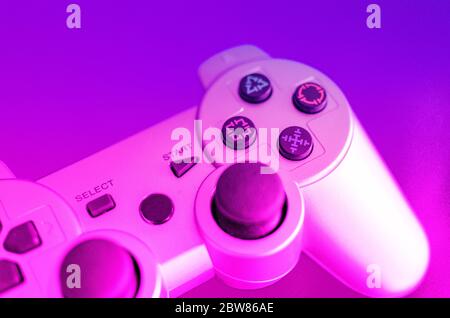 Closeup and selective focus on a button of a video game controller. Blurry background. Pink and blue. Stock Photo