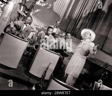 1940s SINGER BANDLEADER AFRICAN AMERICAN CAB CALLOWAY AND FIVE ORCHESTRA MUSICIANS IN PUBLICITY MOVIE STILL FROM STORMY WEATHER - asp fwp1976 ASP001 HARS FILM ROMANCE COMMUNITY URBAN OLD TIME NOSTALGIA OLD FASHION 1 STYLE COMMUNICATION CAREER INSTRUMENTS SINGER TEAMWORK JOY LIFESTYLE ACTOR FIVE HISTORY CELEBRATION CAB 5 JOBS UNITED STATES COPY SPACE FULL-LENGTH HALF-LENGTH DRUMS PERSONS INSPIRATION UNITED STATES OF AMERICA MALES PROFESSION ENTERTAINMENT JIVE STORMY B&W MOVIES MUSICIANS NORTH AMERICA EYE CONTACT NORTH AMERICAN PERFORMING ARTS WIDE ANGLE SKILL OCCUPATION HAPPINESS SKILLS FILMS Stock Photo