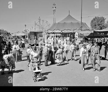 1950s CROWD MEN WOMEN TEENAGERS CHILDREN ATTENDING WALKING ON THE MIDWAY OF THE YORK COUNTY FAIR PENNSYLVANIA USA - f10589 HEL001 HARS ASSEMBLY RURAL COPY SPACE FULL-LENGTH LADIES MASS COUNTY PERSONS MALES CARNIVAL ENTERTAINMENT SPECTATORS B&W GATHERING ADVENTURE LEISURE EXCITEMENT PA RECREATION CAROUSEL MERRY-GO-ROUND COMMONWEALTH KEYSTONE STATE MIDWAY AMUSEMENTS CONCESSIONS JUVENILES RIDES THRONG AMUSEMENT PARK ATTENDANCE BLACK AND WHITE CAUCASIAN ETHNICITY FERRIS WHEEL OLD FASHIONED Stock Photo