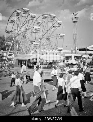 1950s CROWD MEN WOMEN TEENAGERS ATTENDING WALKING ON THE MIDWAY OF THE YORK COUNTY FAIR PENNSYLVANIA USA - f10591 HEL001 HARS JUVENILE MANY STYLE RIDE JOY LIFESTYLE CELEBRATION CROWDS FEMALES ASSEMBLY RURAL COPY SPACE FULL-LENGTH LADIES MASS COUNTY PERSONS MALES CARNIVAL ENTERTAINMENT SPECTATORS B&W GATHERING HAPPINESS ADVENTURE LEISURE EXCITEMENT PA RECREATION COMMONWEALTH VENDER CONCEPTUAL KEYSTONE STATE MIDWAY STYLISH TEENAGED ATTENDING CONCESSIONS JUVENILES RIDES THRONG AMUSEMENT PARK ATTENDANCE BLACK AND WHITE CAUCASIAN ETHNICITY FERRIS WHEEL OLD FASHIONED Stock Photo