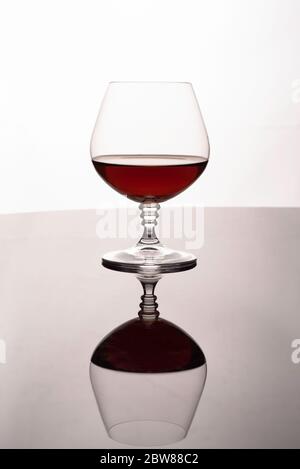 Glass with brandy on a reflective background. Stock Photo