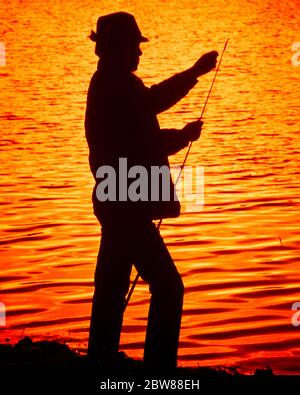 1970s MAN ANONYMOUS AMATEUR FISHERMAN STANDING ON BANK OF RIVER SILHOUETTED AGAINST SUNSET WATER ADJUSTING LINE ON FISHING ROD - ka3730 LAN001 HARS ORANGE OUTLINE CATCHING SKILL ACTIVITY AMUSEMENT HAPPINESS ADVENTURE HOBBY LEISURE SILHOUETTED INTEREST HOBBIES KNOWLEDGE PASSION RECREATION PASTIME REEL PLEASURE CONNECTION CONCEPTUAL ESCAPE ANGLING ANONYMOUS FILTER MID-ADULT MID-ADULT MAN RELAXATION AMATEUR ENJOYMENT OLD FASHIONED Stock Photo