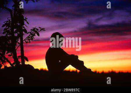 1970s 1980s QUIET BOY CHILD SITTING ALONE ON HILLTOP IN CONTEMPLATION SILHOUETTED FACING MORNING SUNRISE OR EVENING SUNSET  - kj9308 LGA001 HARS RELIGION MOODY RURAL HEALTHINESS HOME LIFE FACING COPY SPACE FULL-LENGTH QUIET INSPIRATION CARING MALES RISK SPIRITUALITY CONFIDENCE TROUBLED CONCERNED MORNING SADNESS GOALS TEMPTATION DREAMS HUNGRY HAPPINESS WELLNESS ADVENTURE DISCOVERY PROTECTION SILHOUETTED COURAGE ABUSED CHOICE KNOWLEDGE POWERFUL PRIDE IN ON AUTHORITY MOOD CONNECTION CONCEPTUAL GLUM SUNRISE CONTEMPLATION ESCAPE FEARFUL IGNORED IMAGINATION OR CREATIVITY GROWTH HILLTOP JUVENILES Stock Photo